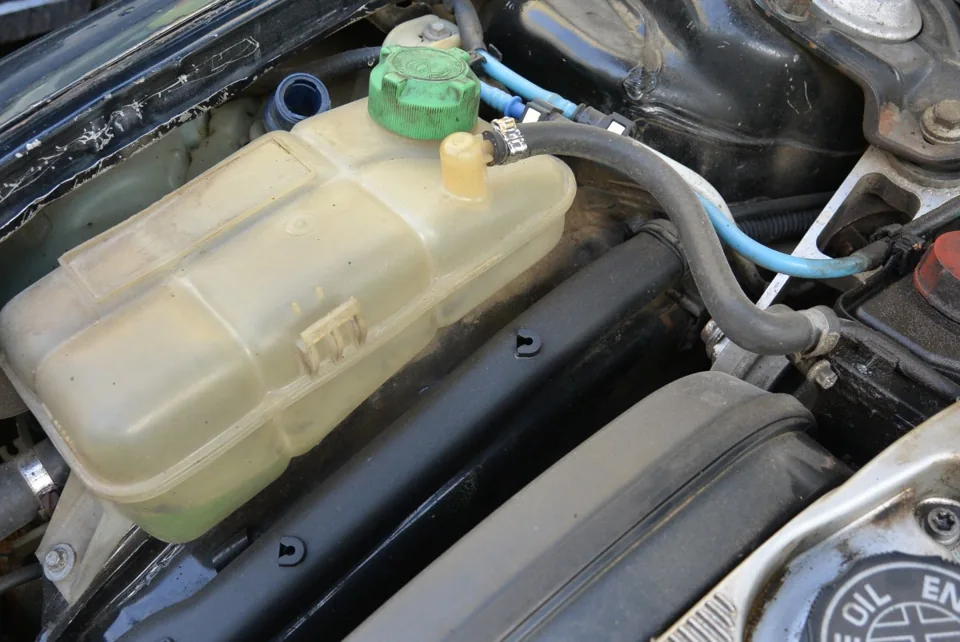 Installed coolant expansion tank with pressure cap and connected coolant hose