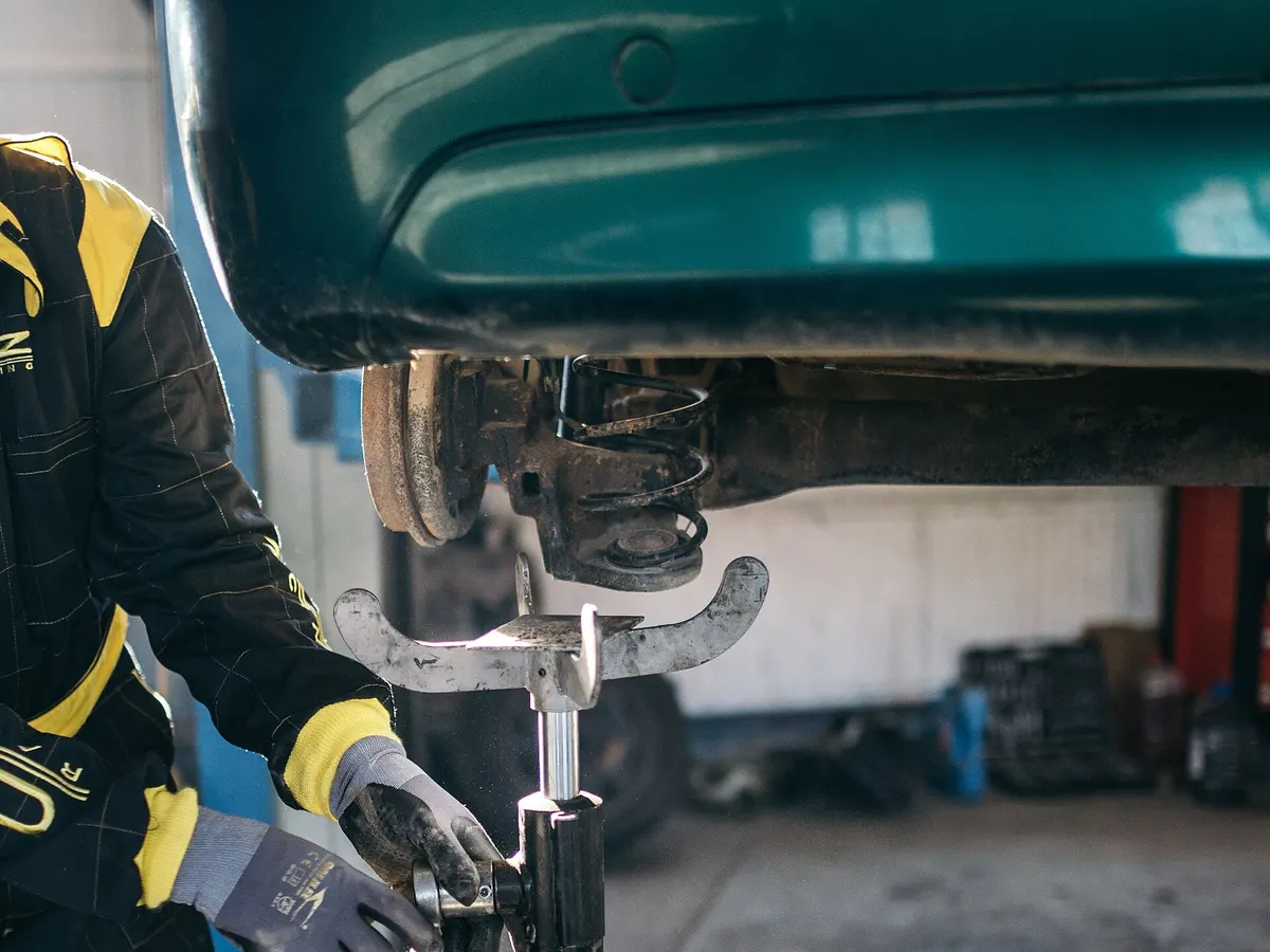 Technician working on a vehicle's coil spring suspension with the car raised on a lift